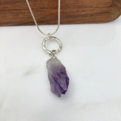 Amethyst rough cut nugget pendant with patterned sterling ring on a sterling snake chain. It's displayed on a small wooden box.
