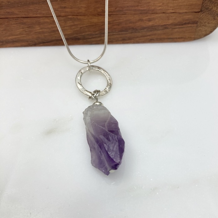 Amethyst rough cut nugget pendant with patterned sterling ring on a sterling snake chain. It's displayed on a small wooden box.