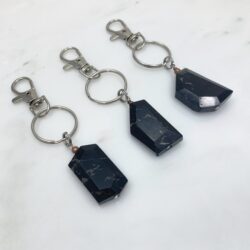 Three black jasper keyring with five or six sides. The jasper has pale brown inclusions. The keyrings have detachable hooks.