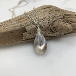 Baroque freshwater pearl pendant displayed on a small piece of driftwood.